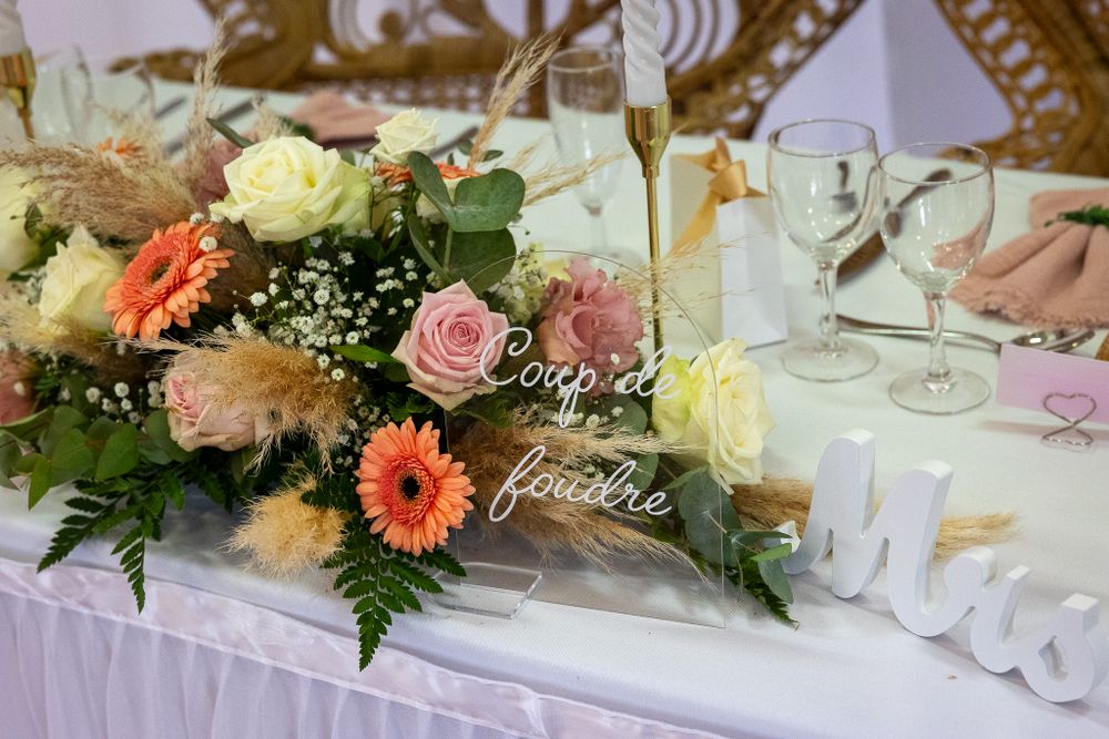 Decorated wedding reception tables with pink and coral floral centerpieces and white table settings.