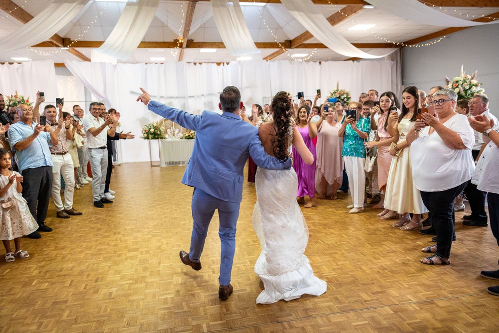Wedding reception celebration with guests dancing in a circle on a hardwood dance floor.