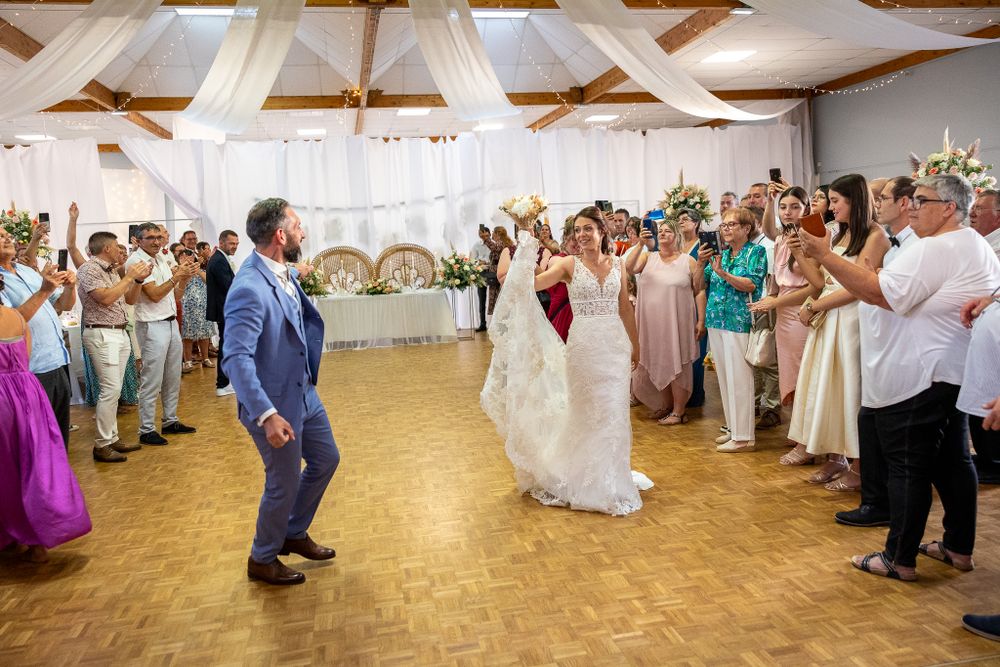 Panoramic view of wedding guests dancing and celebrating in a decorated reception hall.