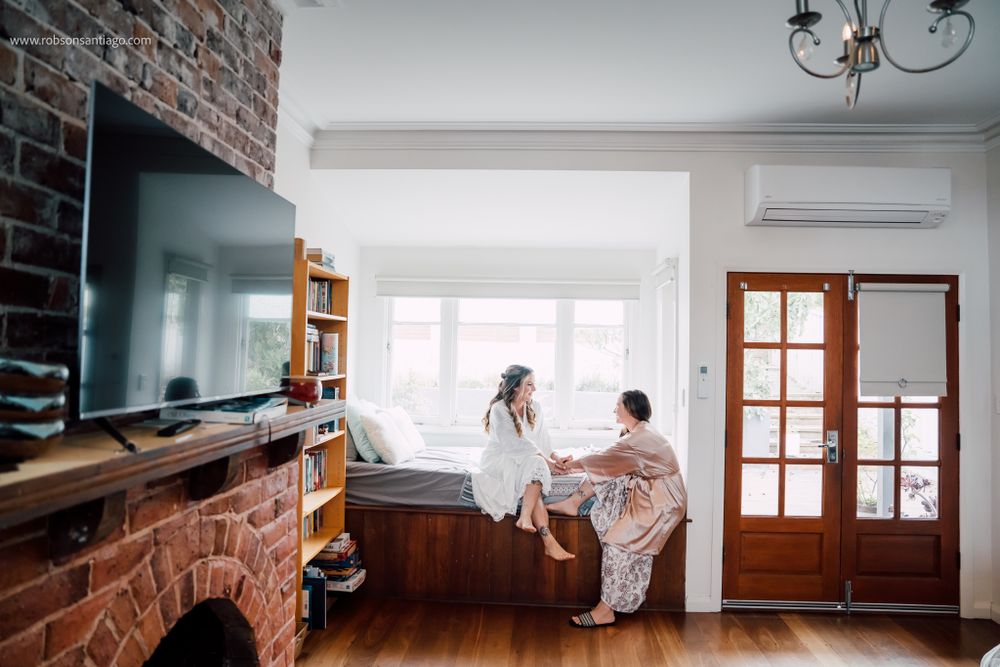 Cozy living room interior with exposed brick wall, flatscreen TV, and built-in window seat nook by bright windows.