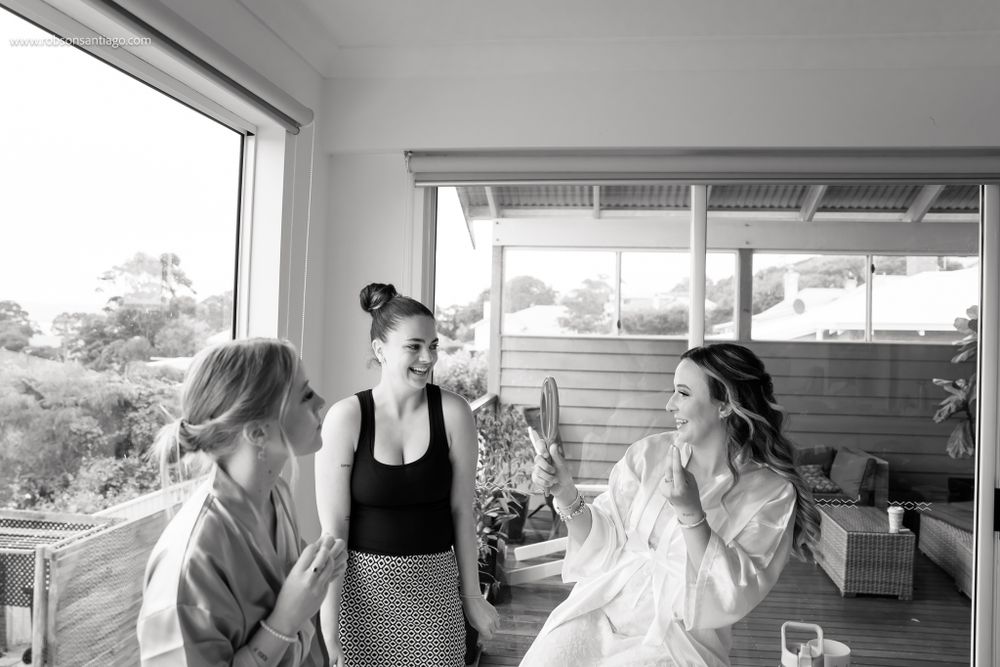 Three people share a relaxed moment together on a covered porch with natural light streaming through windows.