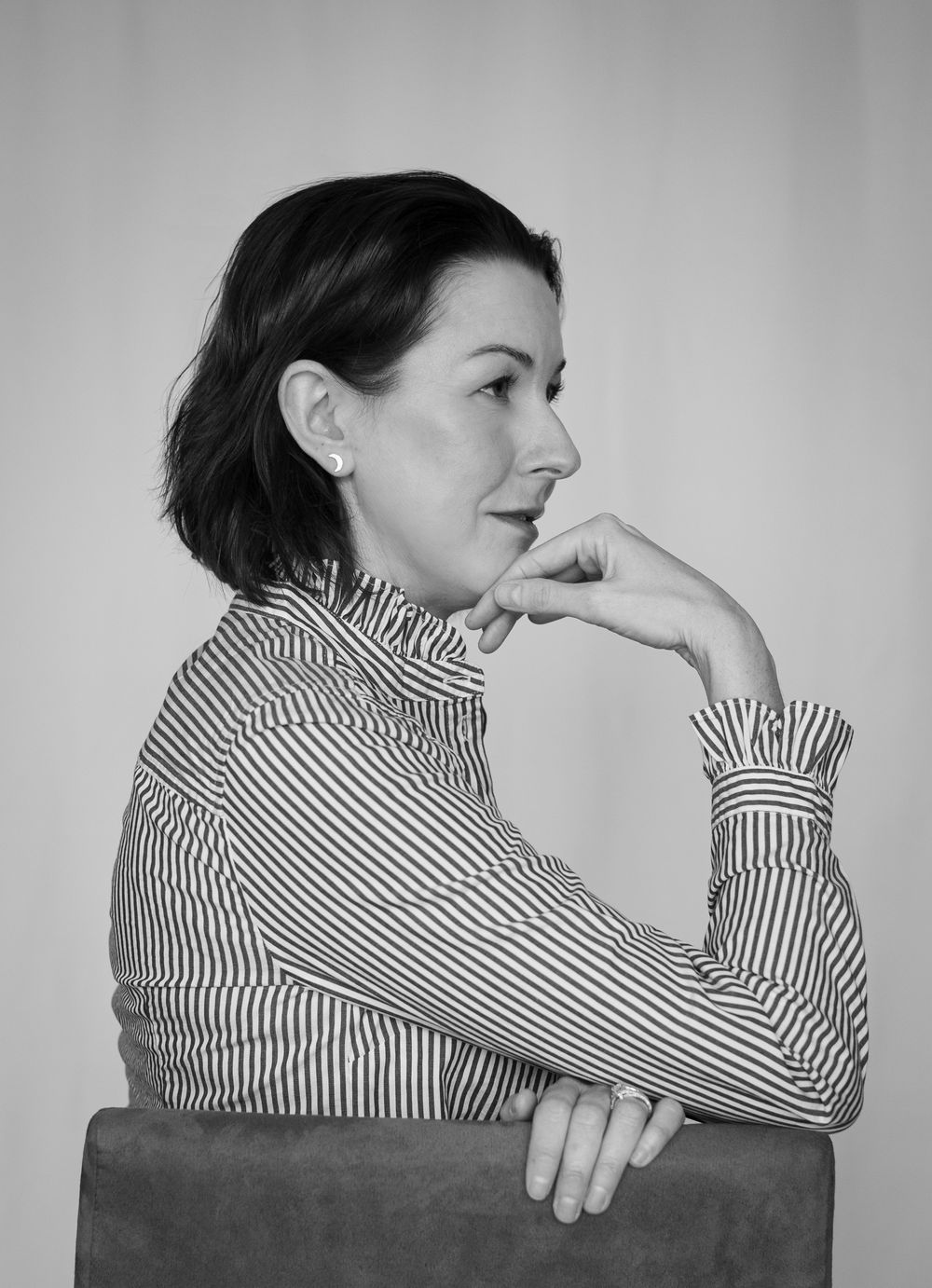 Black and white portrait of a person in striped collared shirt looking contemplative.