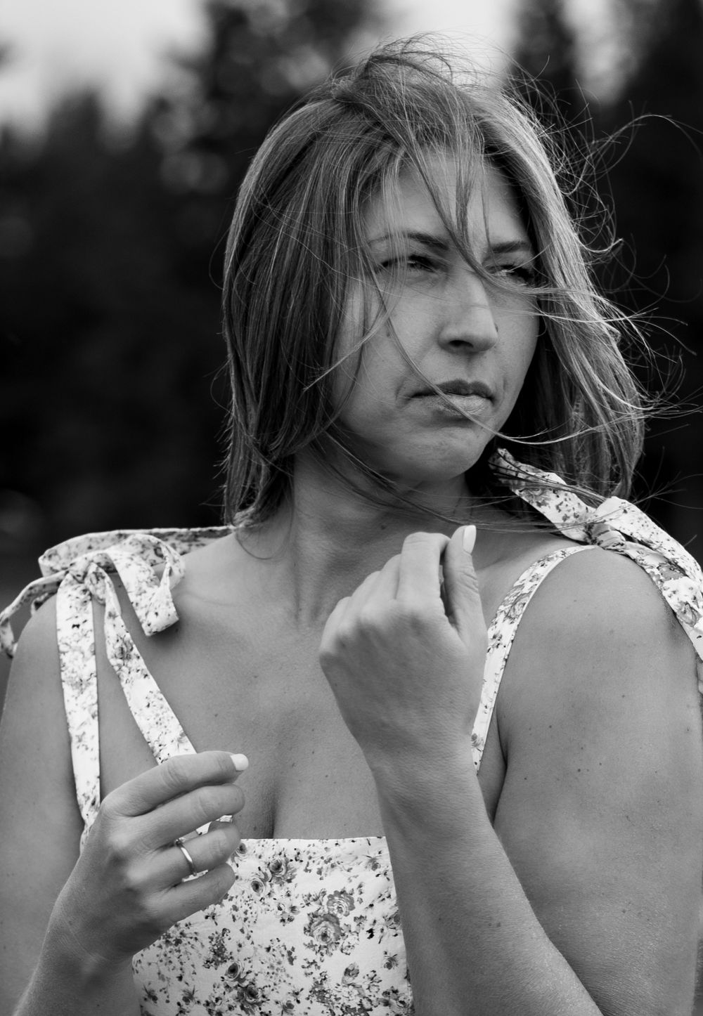 Black and white portrait of a person in floral dress looking away thoughtfully.