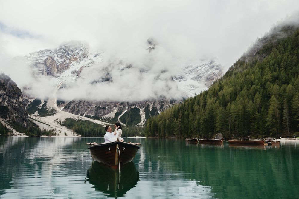 A panoramic mountain landscape with snow-capped peaks reflected in the turquoise waters of an alpine lake.