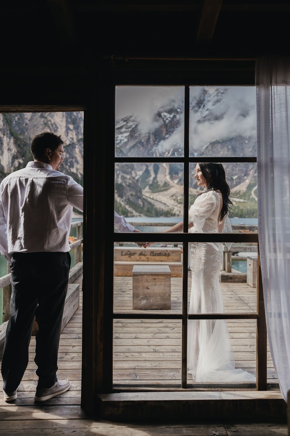 Silhouetted couple looking through large window frame at dramatic mountain landscape views.