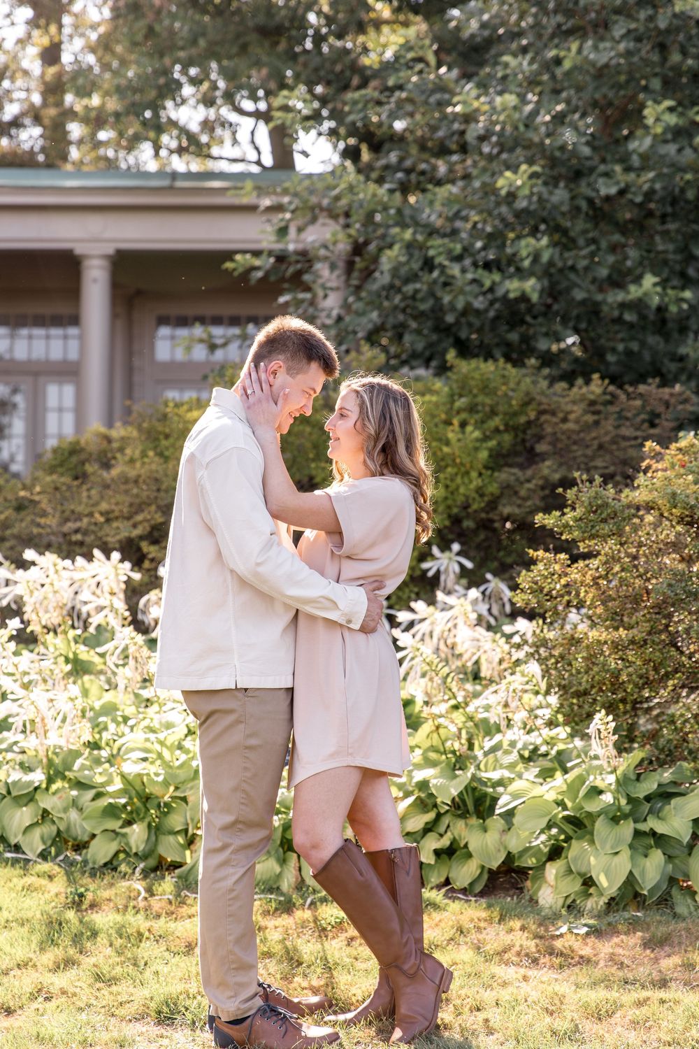 A couple shares a romantic moment in a garden with green foliage creating a natural backdrop during golden hour.
