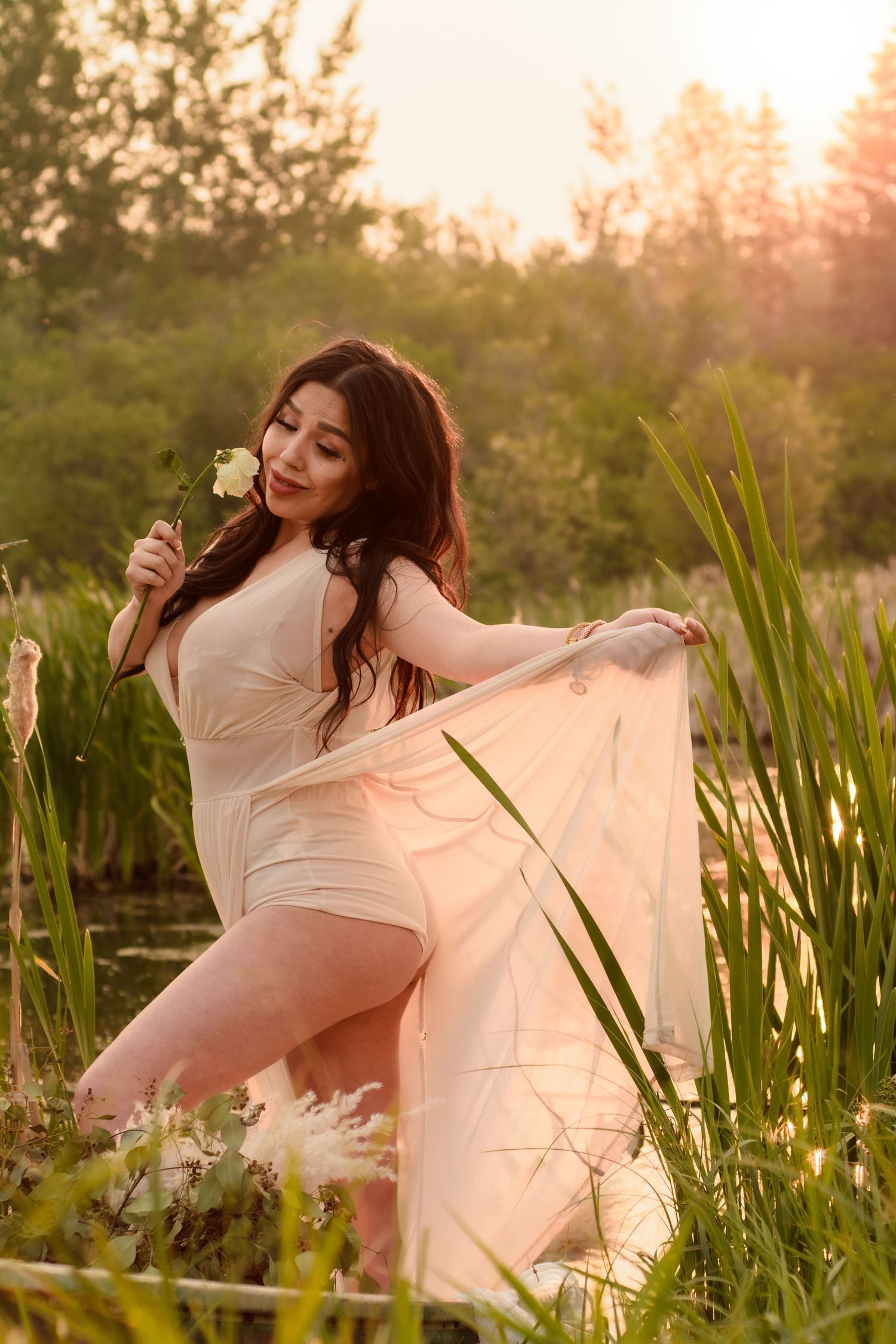 Ethereal sunset portrait in a marsh with flowing fabric and tall grass during magic hour.