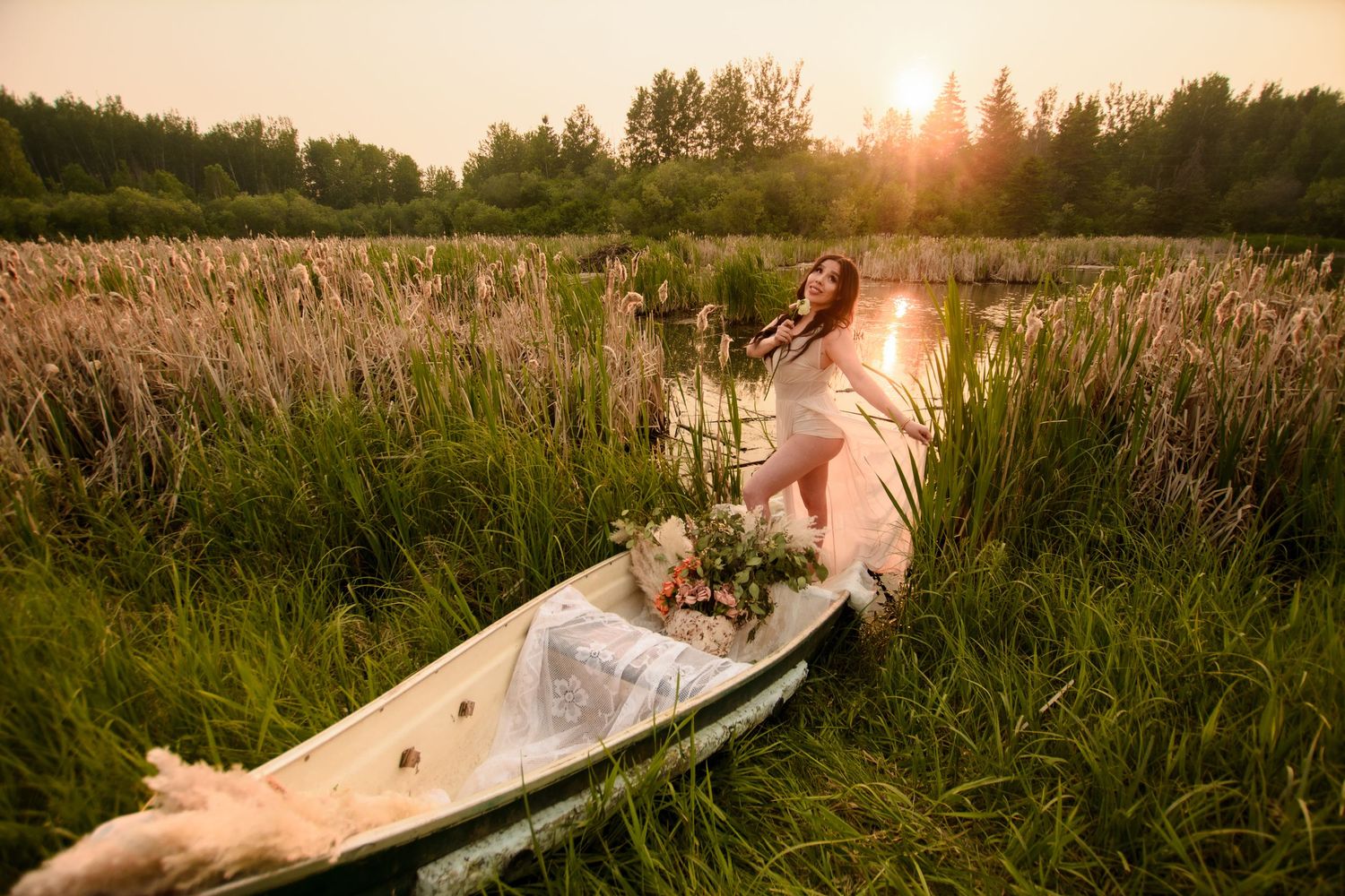 Golden sunset illuminates tall grasses in a wetland marsh as someone paddles a white canoe through the tranquil waters.