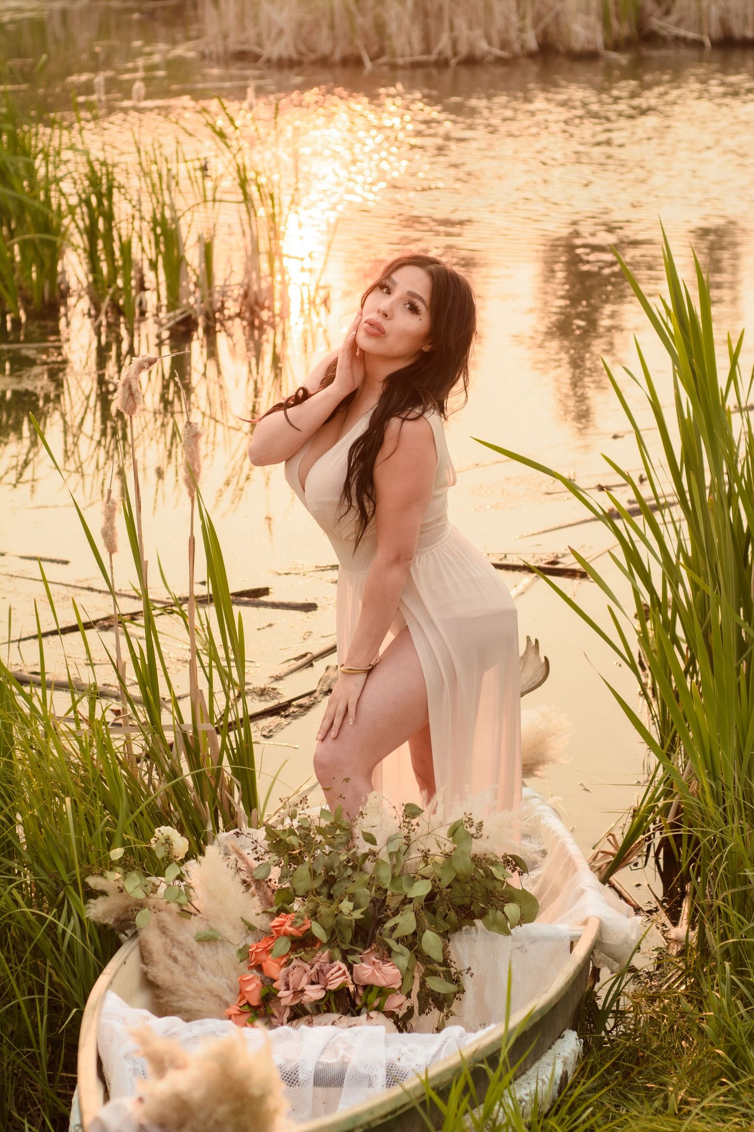 A dreamy photoshoot in a pond with white dress and floral decorations during golden hour.