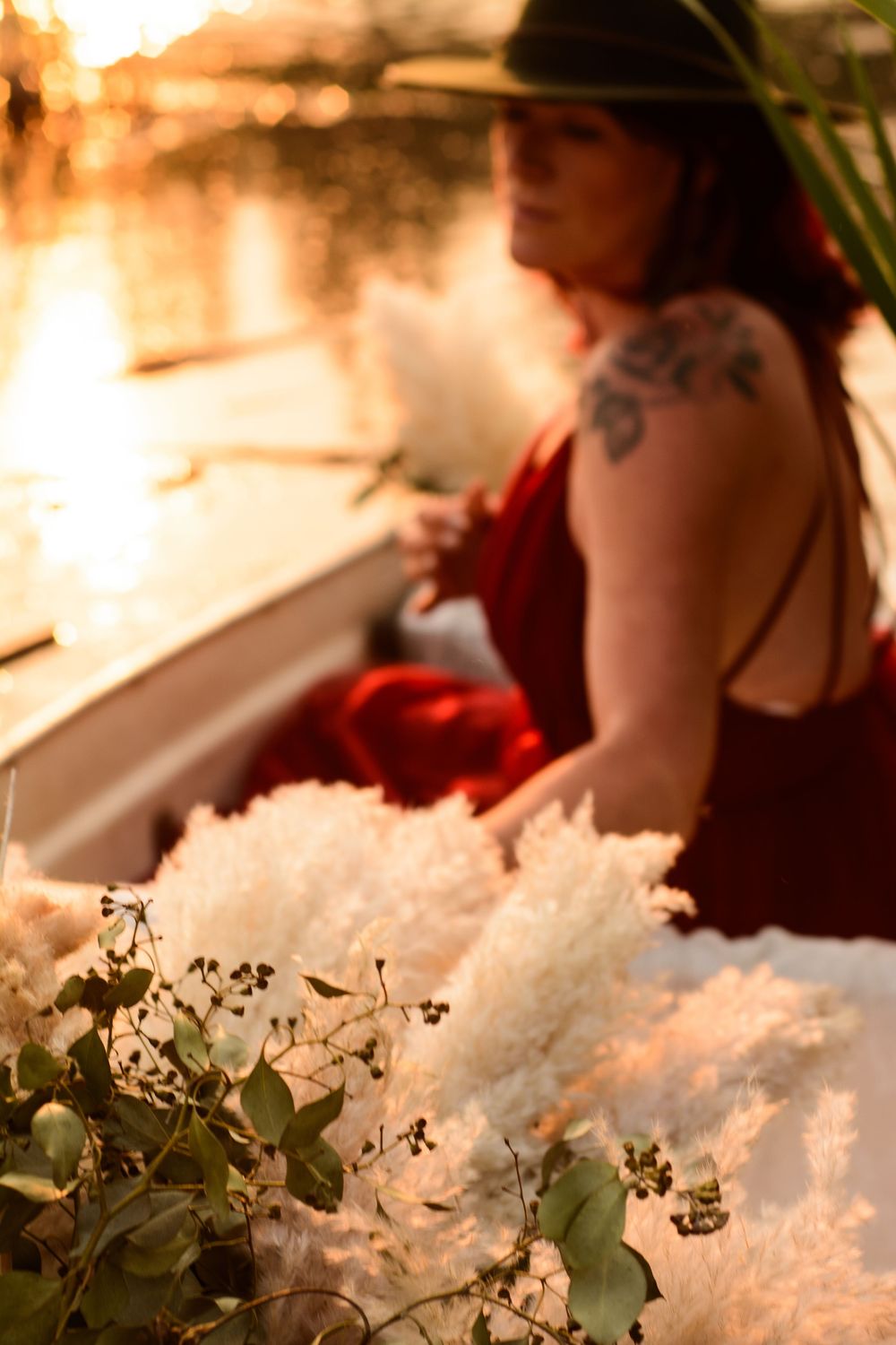 A wedding detail shot featuring delicate white floral arrangements and greenery in warm sunlit lighting.