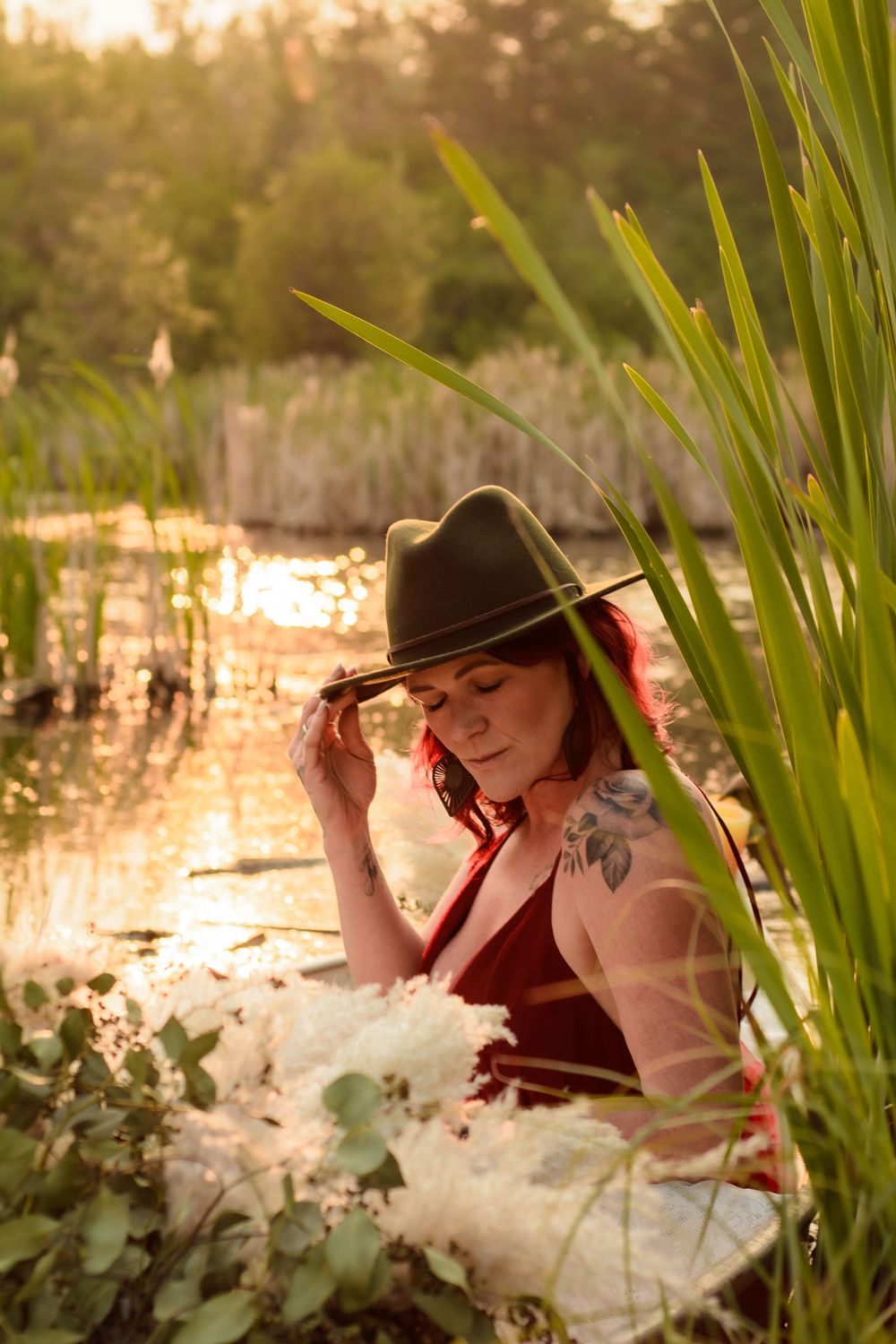 A dreamy outdoor portrait captured in soft golden light with cattails and water in the background.
