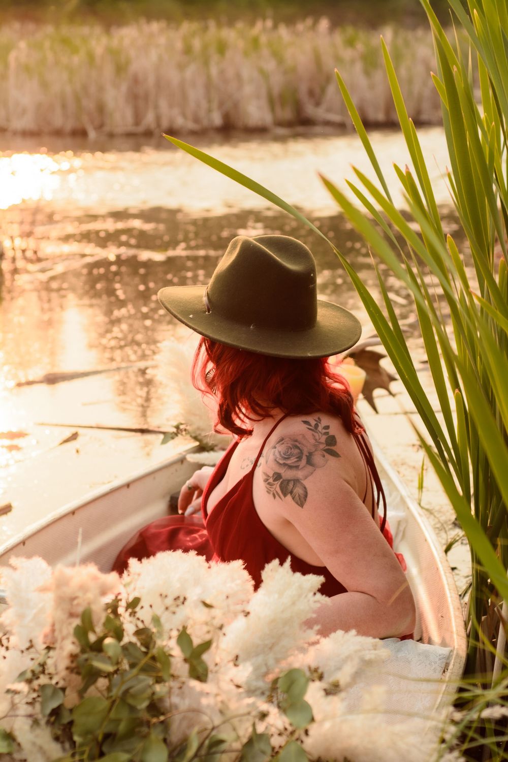 Artistic portrait by a pond with cattails and natural light creating a romantic vintage mood.