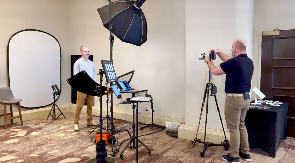 Professional photo studio setup showing photographer capturing headshots with lighting equipment and reflector screen.