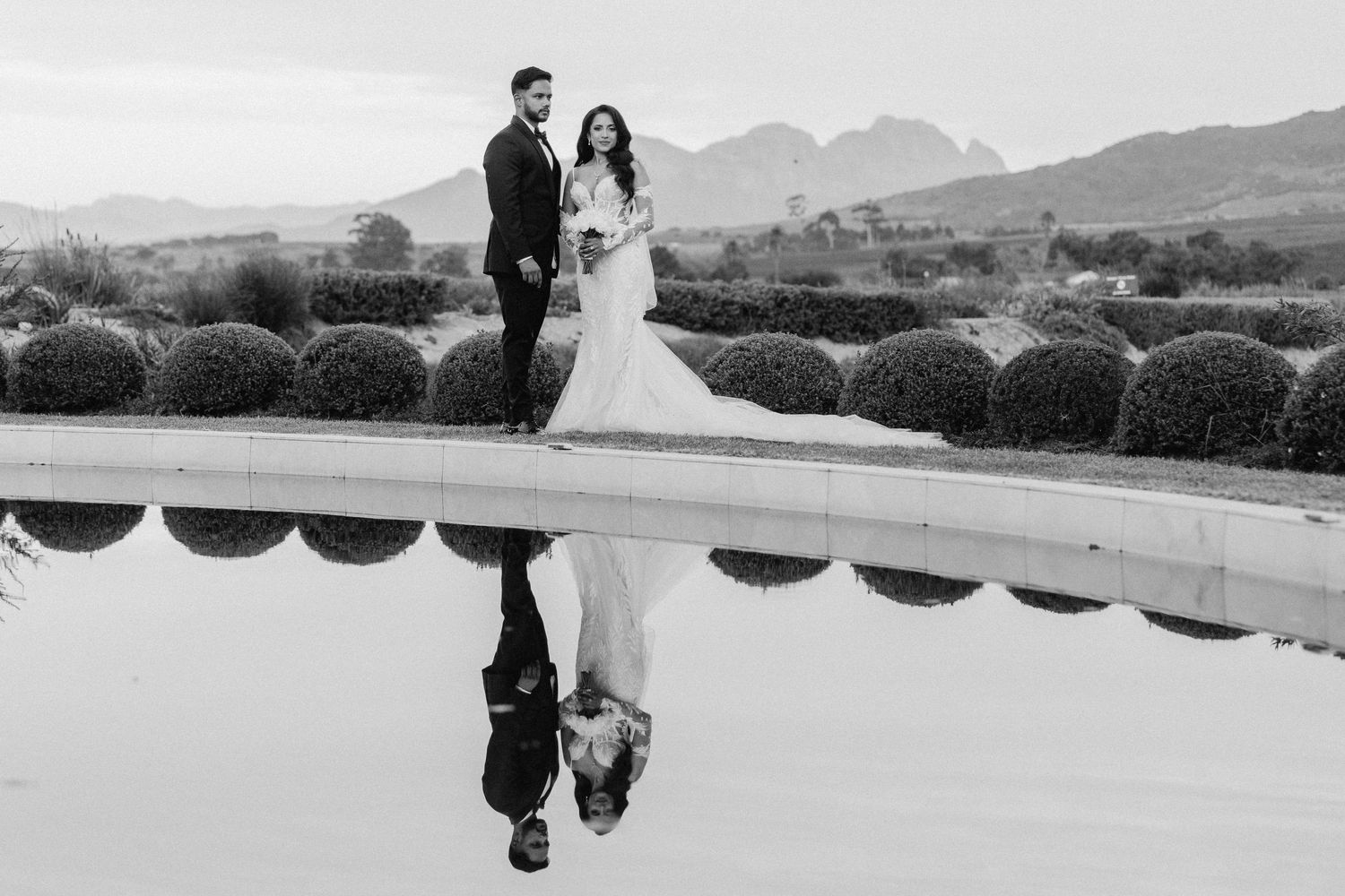 A wedding couple and their reflection captured in black and white at a scenic mountain venue.