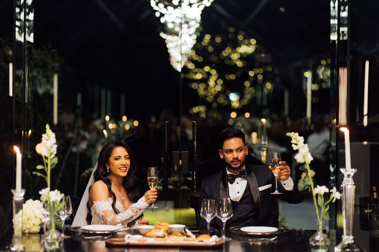 A couple enjoys an elegant candlelit dinner at a romantic venue with wine glasses and formal attire.