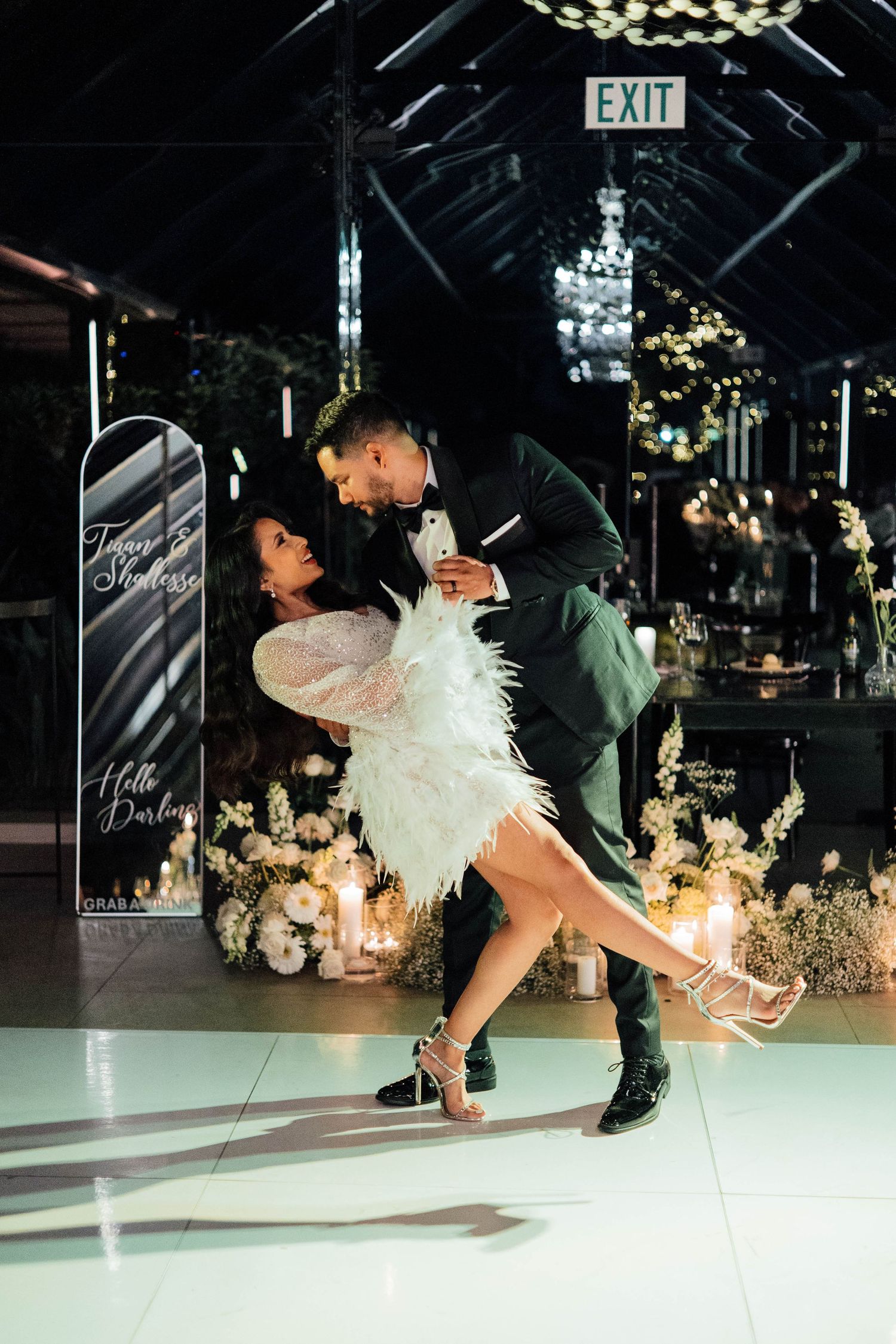 Two people performing an elegant dance dip move on a glowing dance floor surrounded by romantic floral decorations.