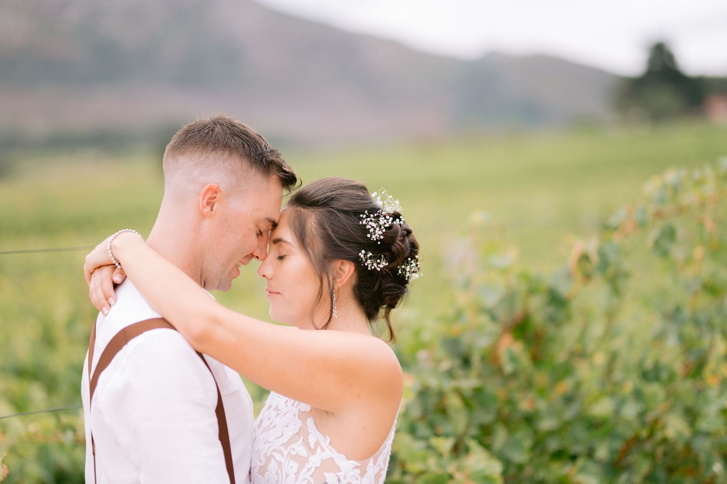Romantic wedding couple embraces in a wildflower field during golden hour.