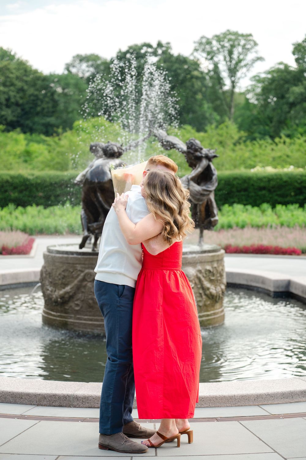 A couple hugs after their engagement in the Conservatory Gardens of Central Park. A tender moment captured by Joliette Marie Photography.