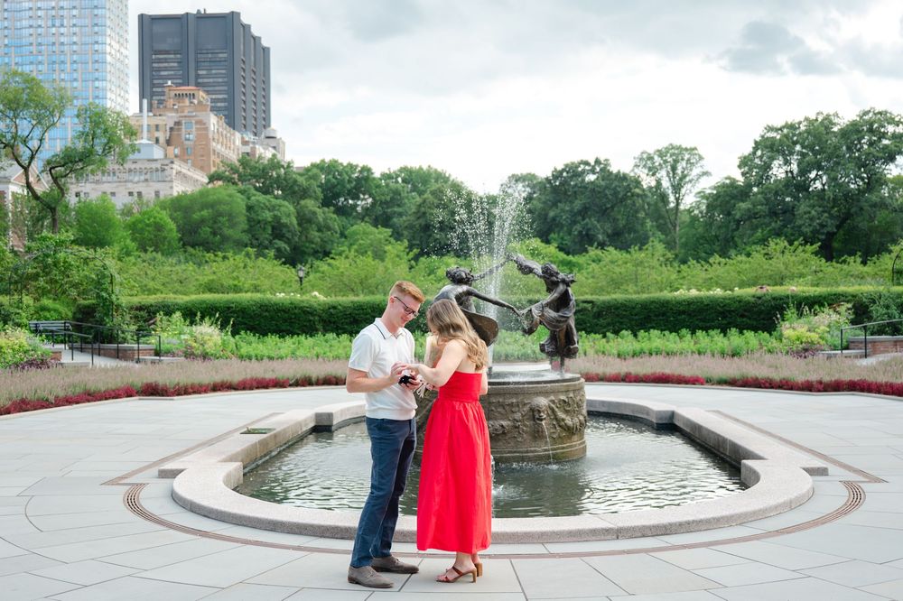 A romantic photoshoot with a couple at a scenic fountain and garden setting with beautiful urban architecture and greenery.