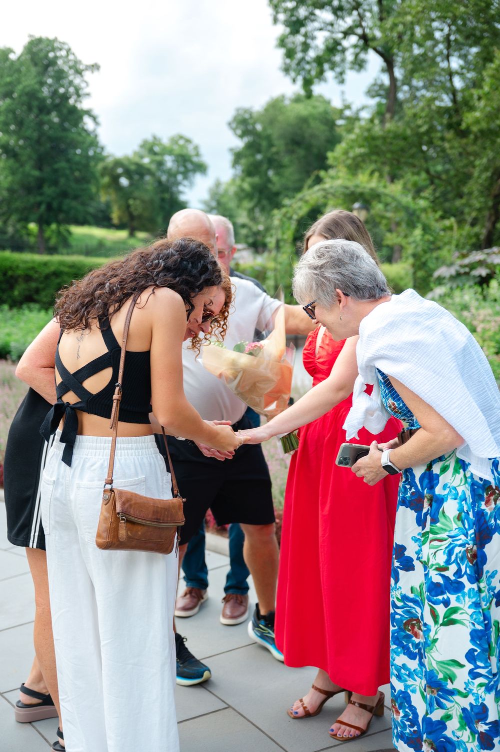 A family gathered together admiring a girl's new engagement ring after saying yes to a marriage proposal in NYC.