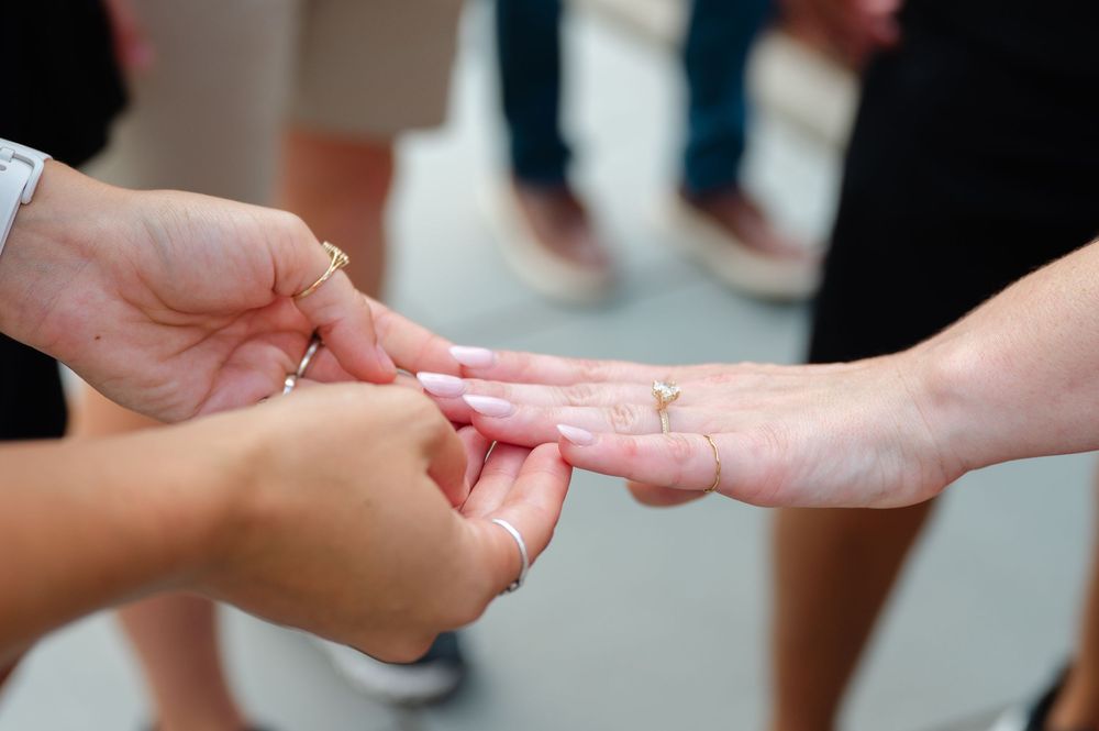 Someone gently hold's a woman's hand with a new engagement ring on it.