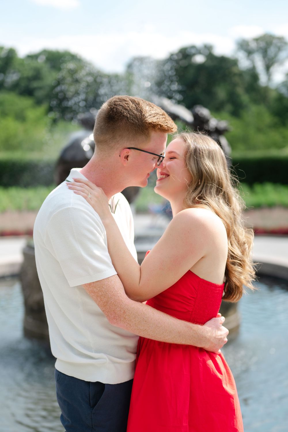 Couple smiles at each other and embraces during their proposal session in Conservatory Gardens of Central Park.
