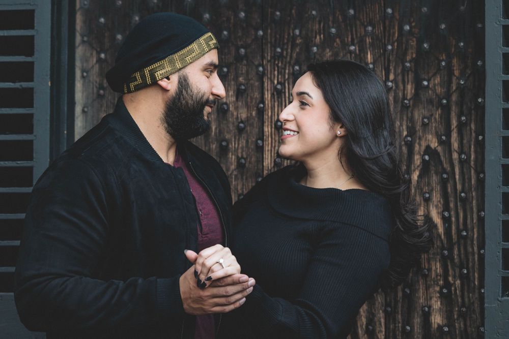 A couple shares a laugh while holding hands during their engagement photoshoot.