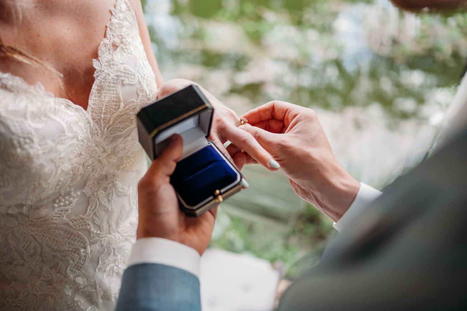 Wedding ceremony moment with hands holding a small ring box during the exchange of rings.