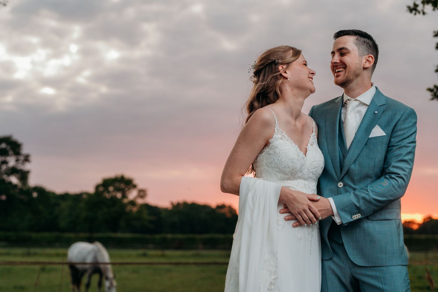 A sunset wedding portrait shows a couple in an outdoor setting with golden light and a horse in the distant field.
