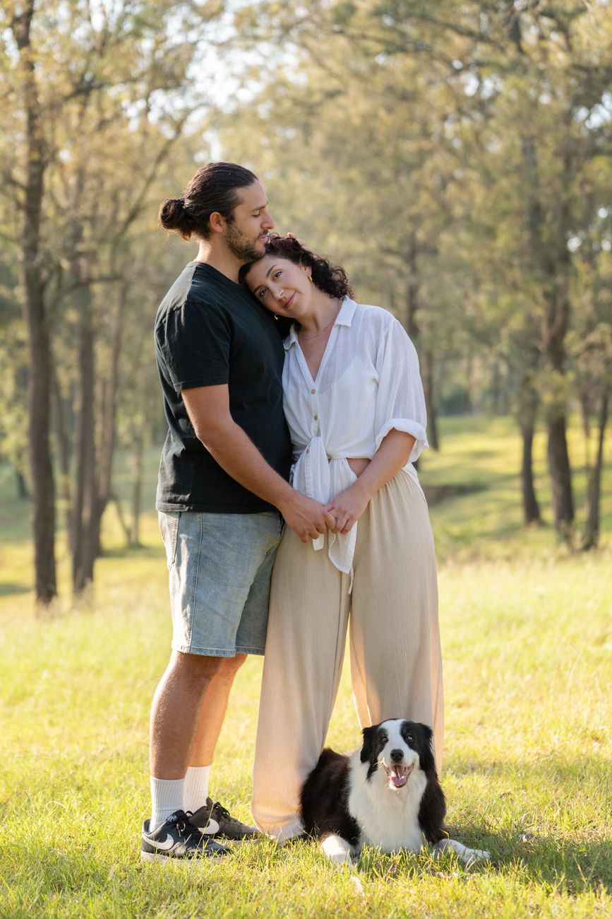 couple softly hug while their dog is laying in between them during their photoshoot