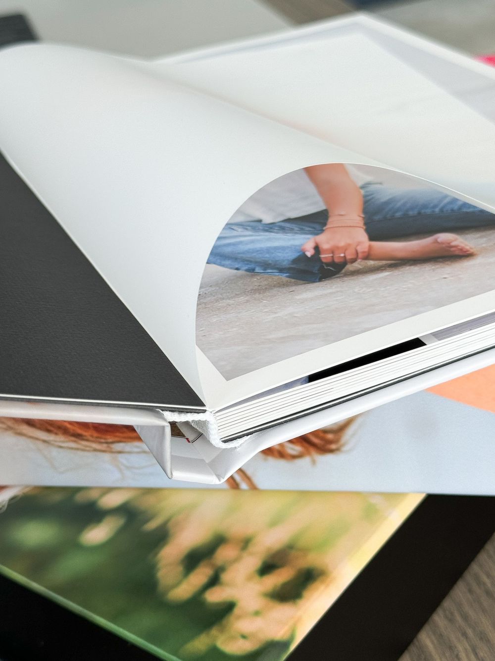 Close-up view of photo prints and albums being arranged on a wooden surface with curled pages visible.