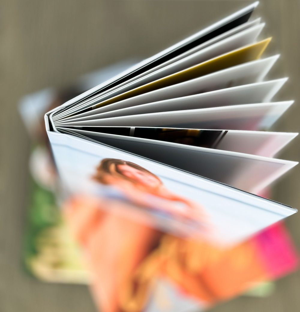 Close-up view of an open book or photo album showing fanned out pages with blurred background.