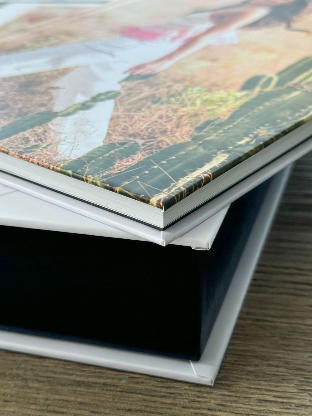Close-up of a stack of books or magazines showing the layered spine edges on a wooden surface.