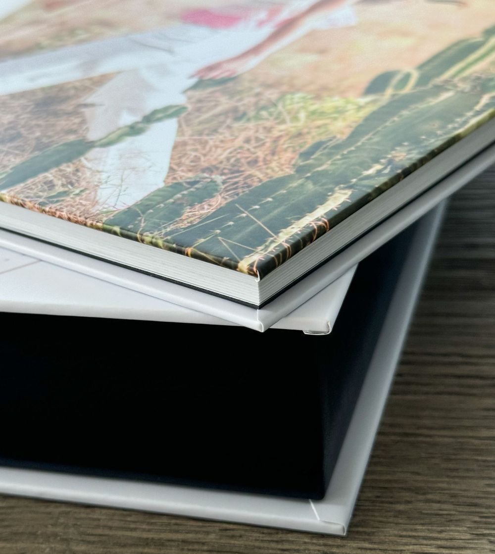 Close-up of stacked books or magazines showing worn binding edges on a dark wooden surface.