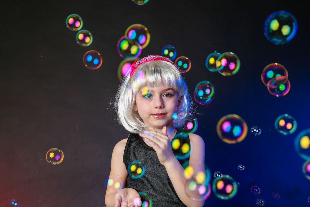 Colorful soap bubbles float around a subject in a dark setting with dramatic lighting.