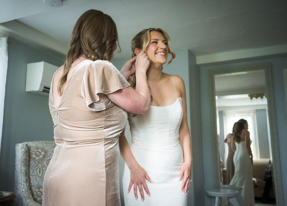 A group stands together during a wedding celebration wearing blush pink and white formal dresses in an elegant indoor setting.