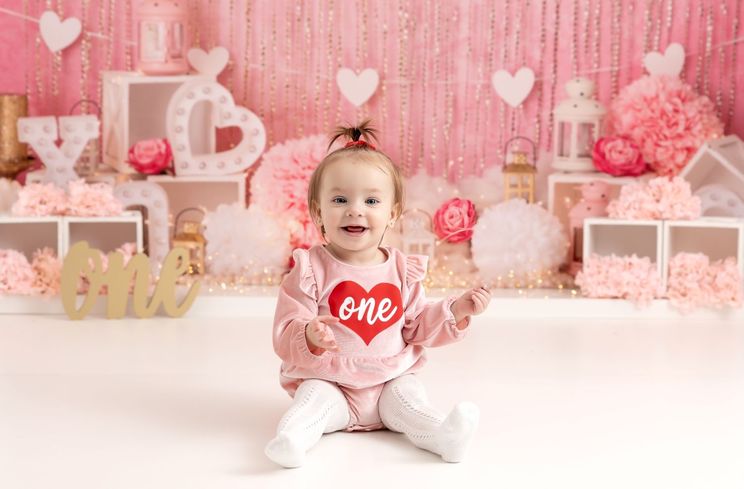 Pink Valentine's Day themed photo setup with white decorative elements, hearts, and romantic details in soft pastel tones.