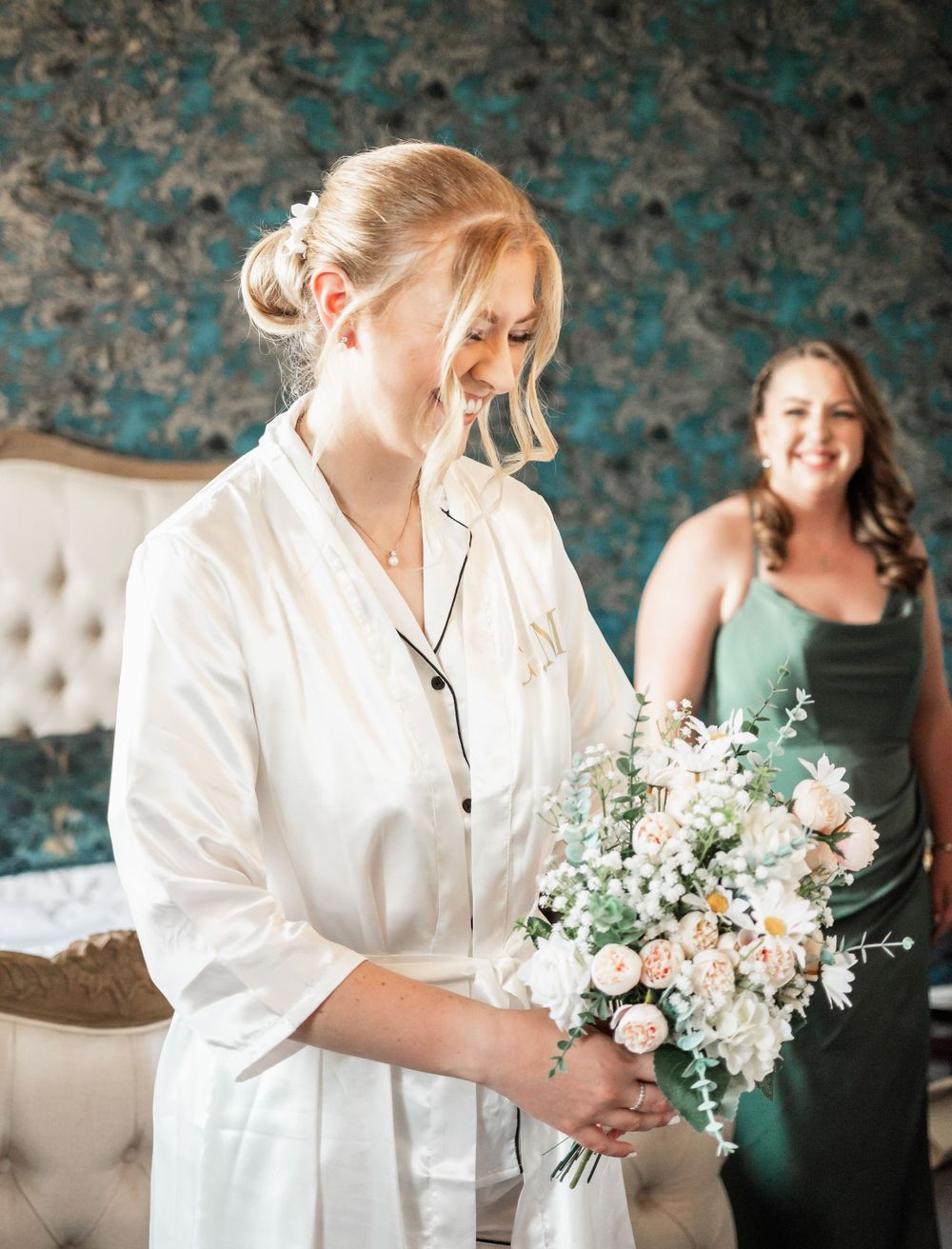 Bridal preparations in elegant room with teal wallpaper showing delicate floral bouquet.