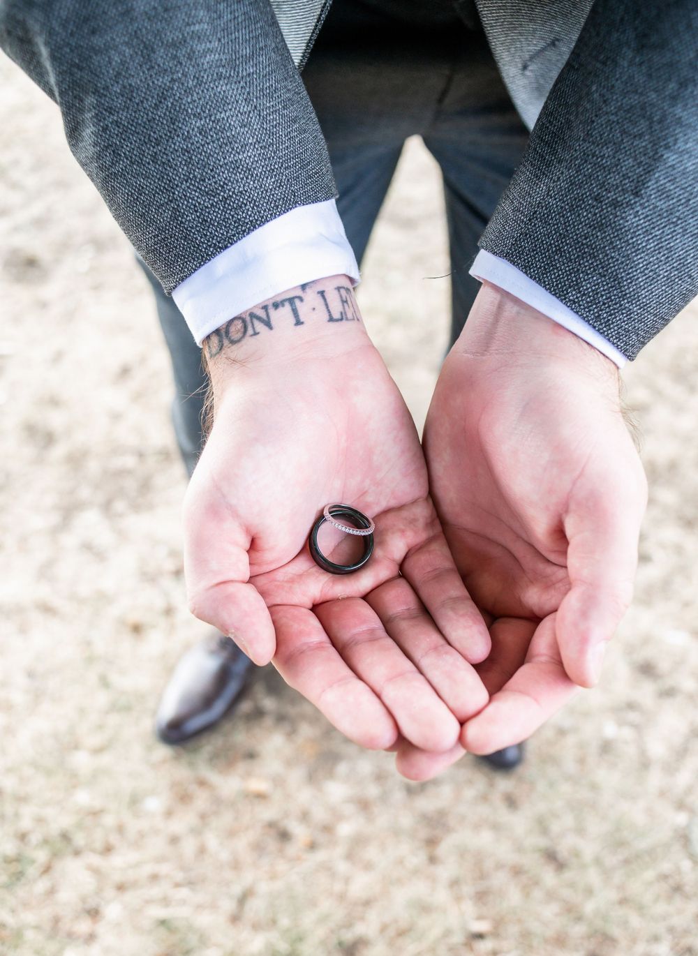 Close up of hands holding wedding ring with "Don't" visible on sock.