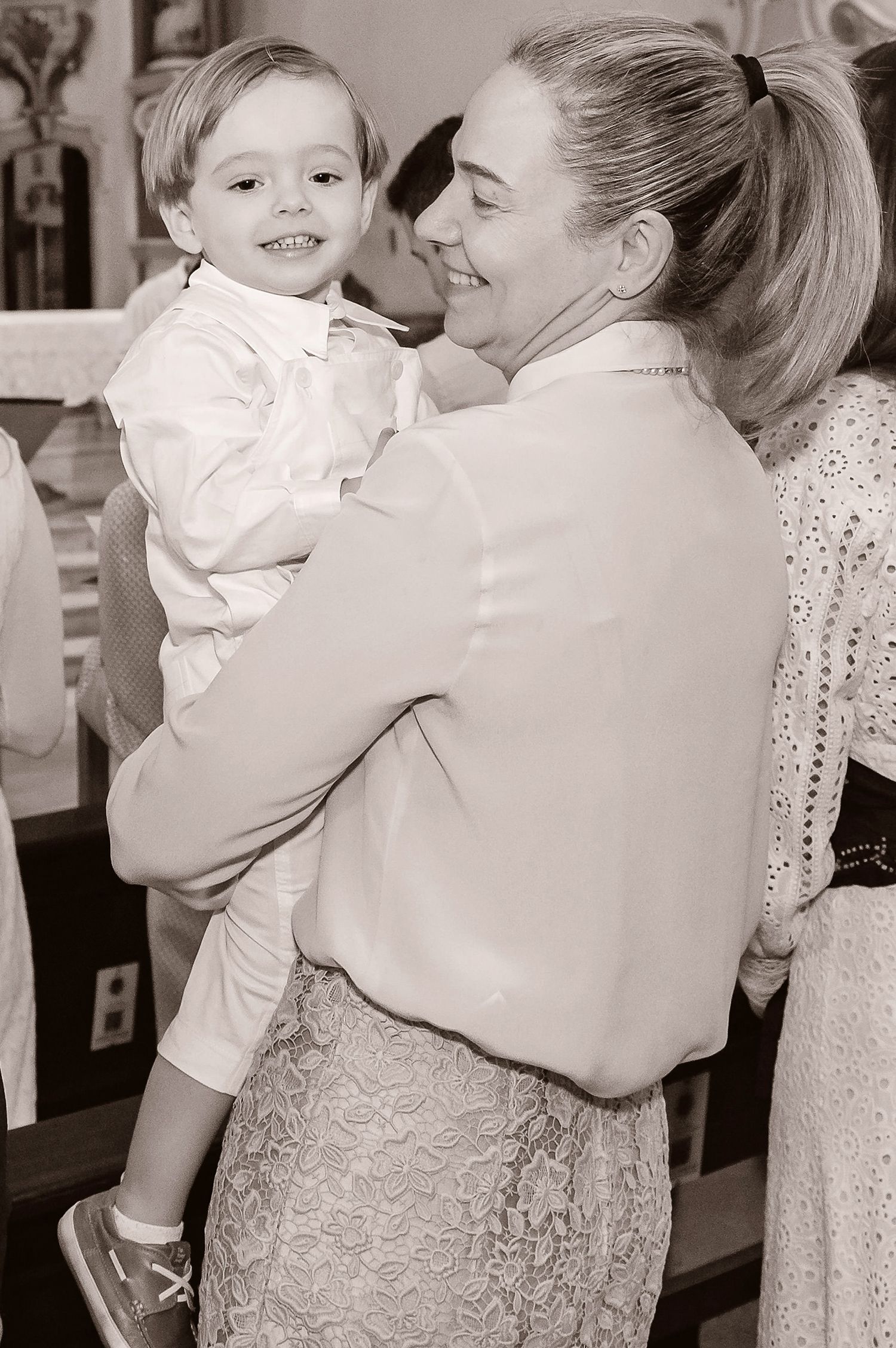 Black and white candid photograph of a tender embrace during a formal church celebration.