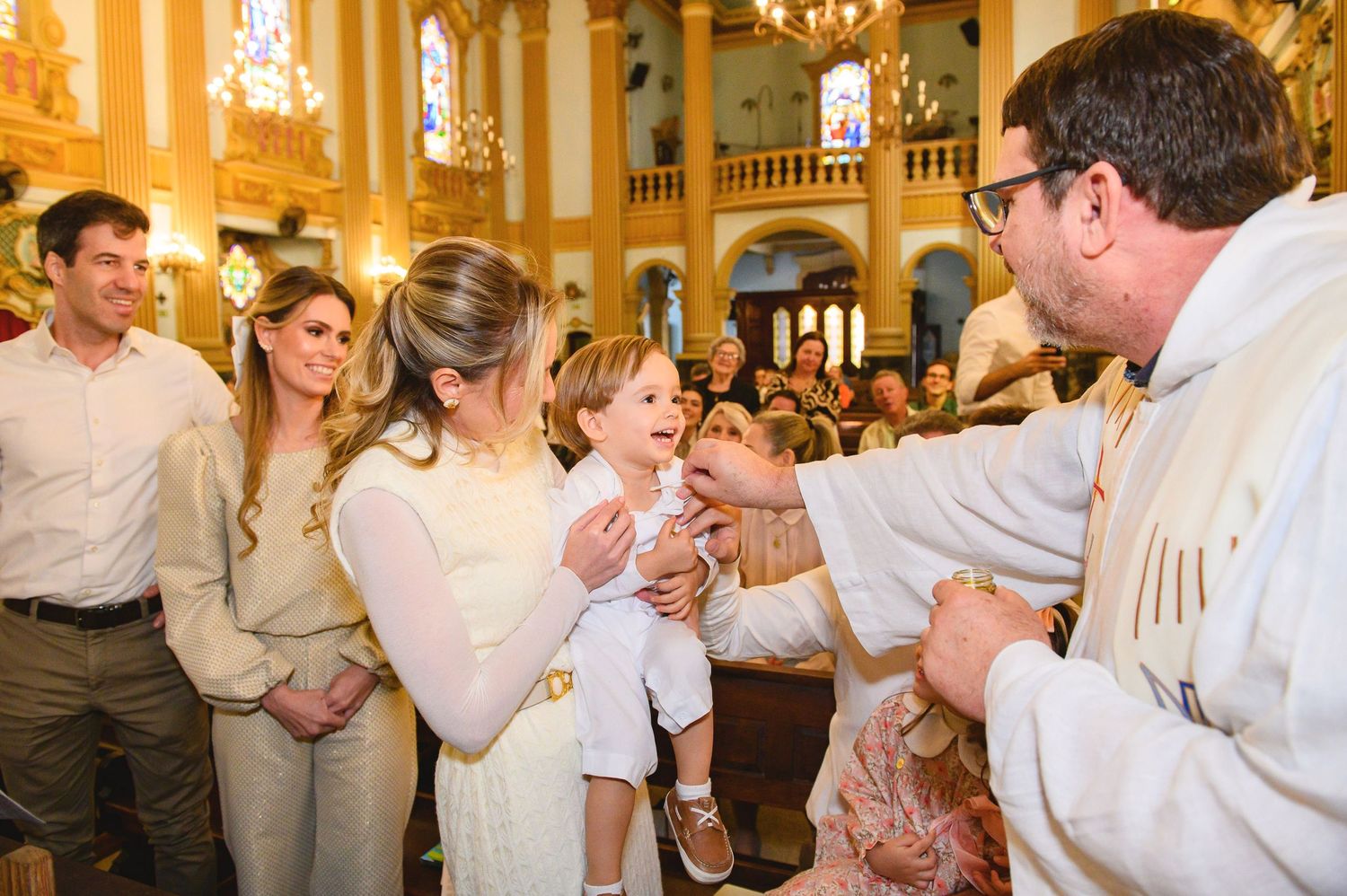 A religious ceremony takes place inside an ornate church with golden walls and chandeliers.