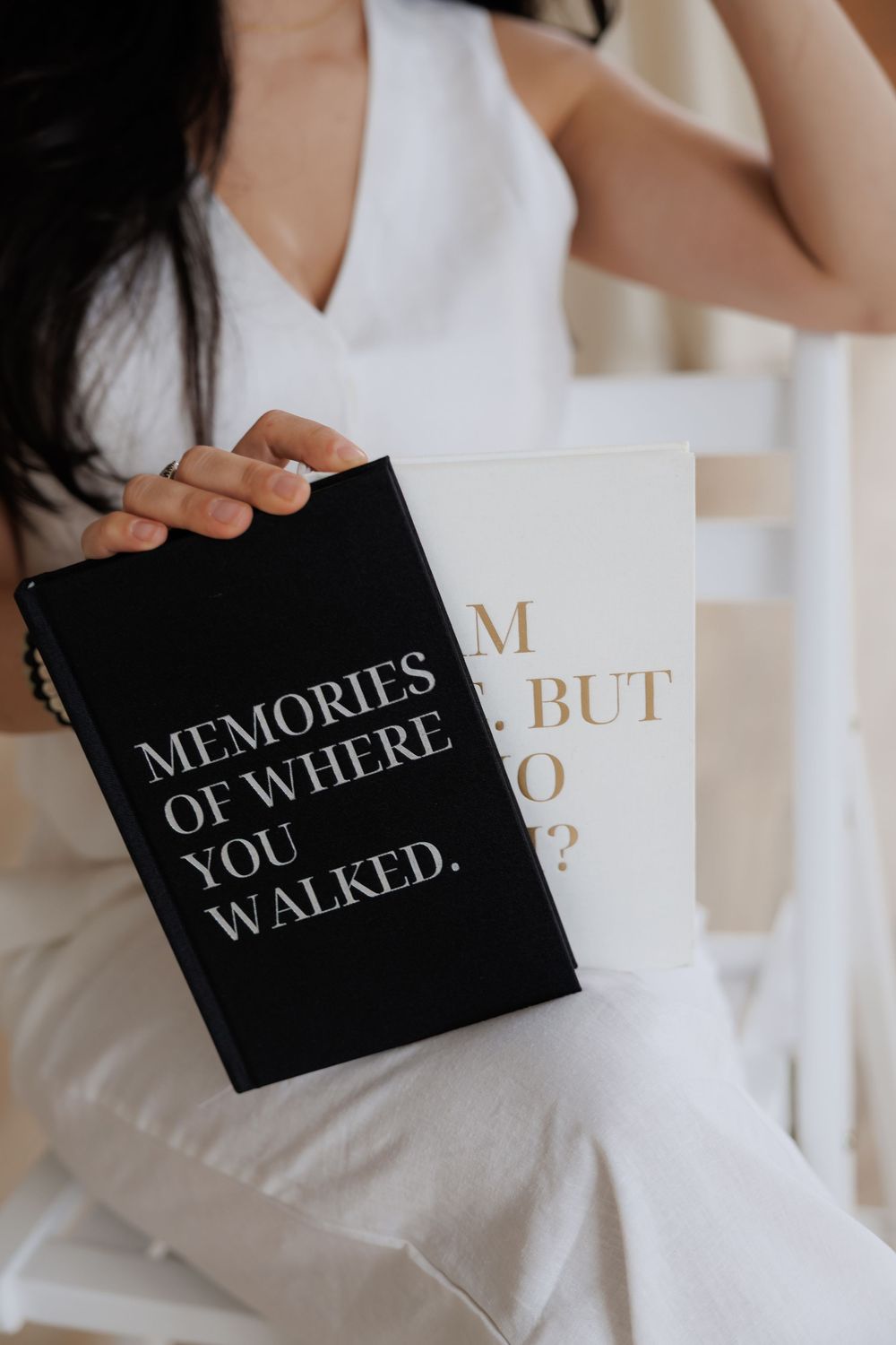 Close-up of hands holding black and gold books with poetic titles against white background.