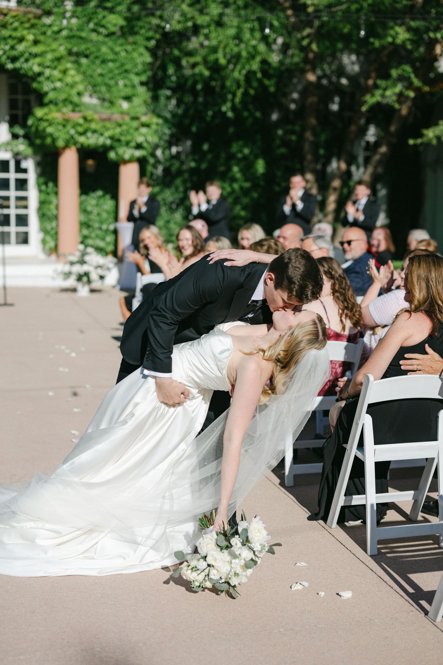 A dramatic dip at a wedding ceremony with a white dress and floral bouquet on the ground.