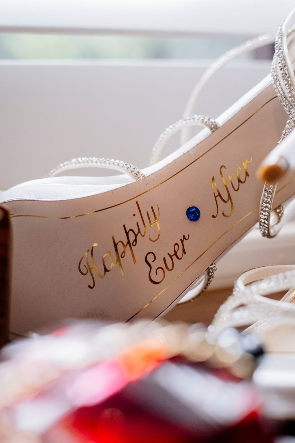 Wedding shoe sole with "Happily Ever After" written in elegant gold script and adorned with rhinestone straps.