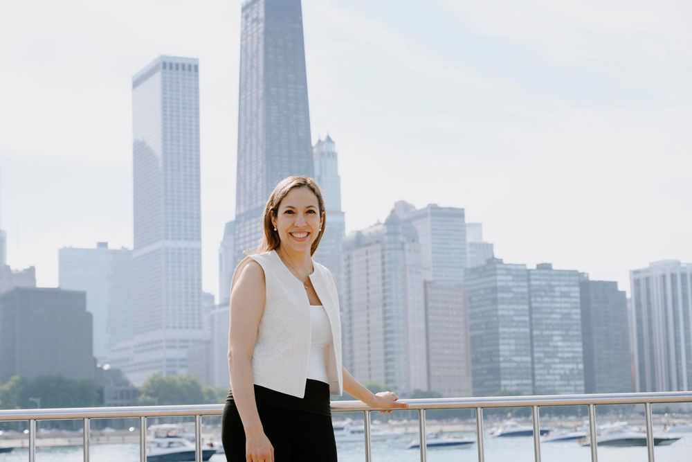 A professional stands on a rooftop terrace with the dramatic Chicago skyline featuring skyscrapers in the background.