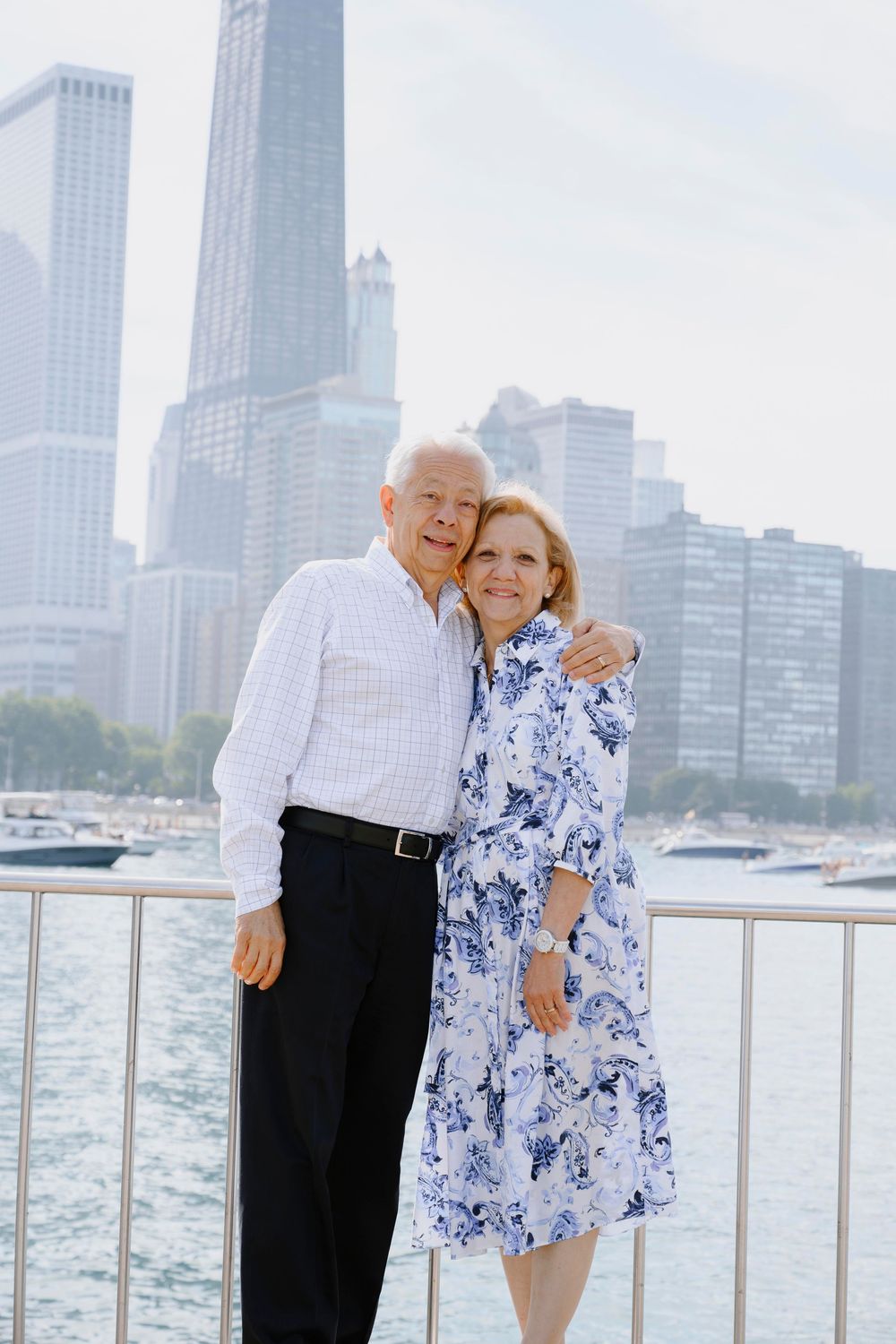 A couple embraces by the Chicago waterfront with the iconic skyline in the background.