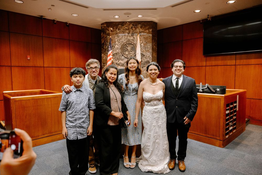 Small group celebrates together inside a wood-paneled courthouse interior with stone accent wall.