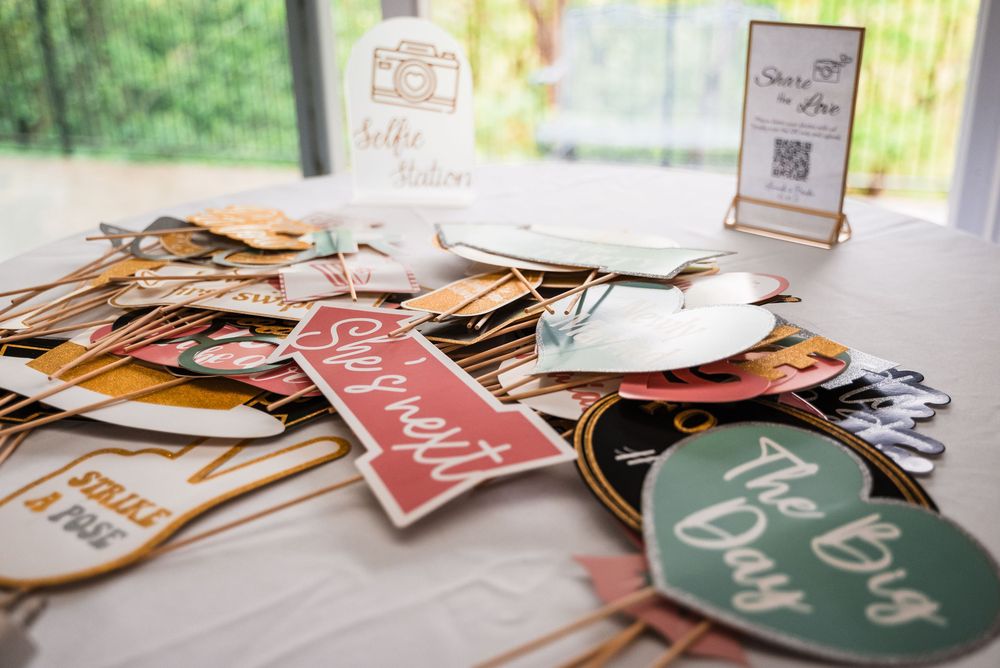 Collection of colorful wedding photo booth props arranged on a white tablecloth.