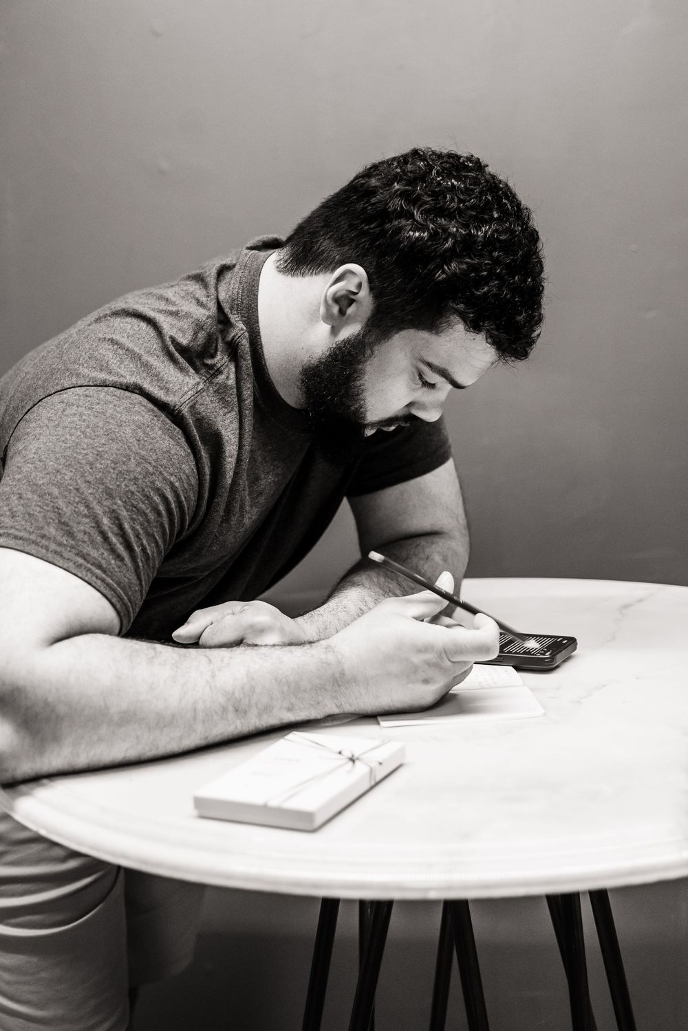 Person in casual attire focused on writing or texting at a round table.