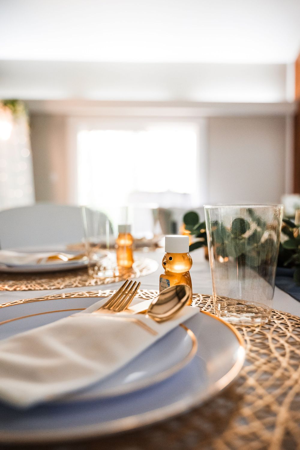 Elegant place setting with gold chargers, white plates and glowing candles on a wedding reception table.